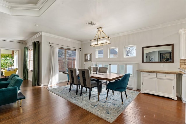 dining room with crown molding, dark hardwood / wood-style floors, and a chandelier