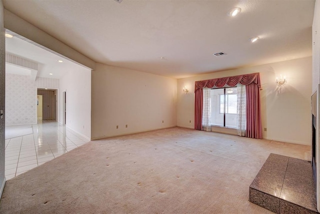 empty room with light colored carpet and a tile fireplace