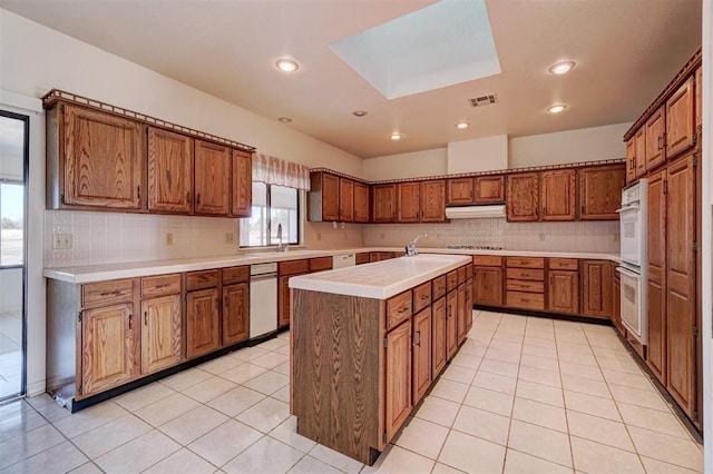 kitchen featuring sink, a center island with sink, light tile patterned floors, gas cooktop, and double oven