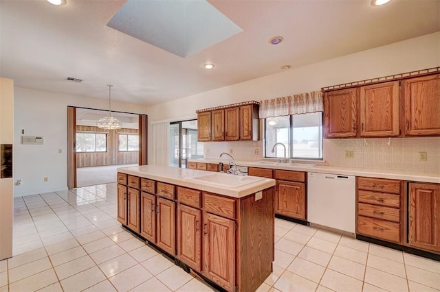 kitchen featuring pendant lighting, sink, dishwasher, an island with sink, and decorative backsplash