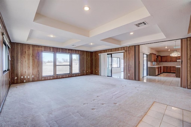 unfurnished living room featuring a raised ceiling, light carpet, and wood walls