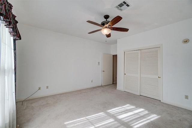 unfurnished bedroom featuring light colored carpet, a closet, and ceiling fan