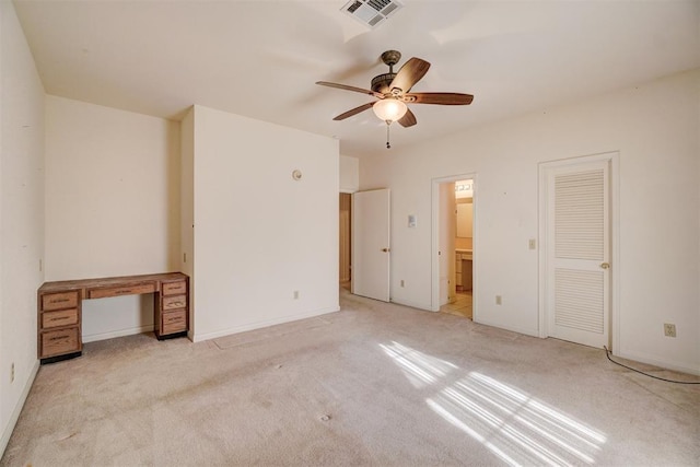 unfurnished bedroom featuring connected bathroom, light colored carpet, and ceiling fan