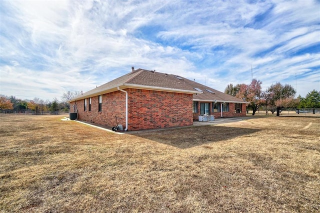 view of side of home with cooling unit, a lawn, and a patio area