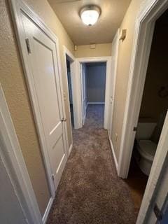 hallway featuring dark colored carpet