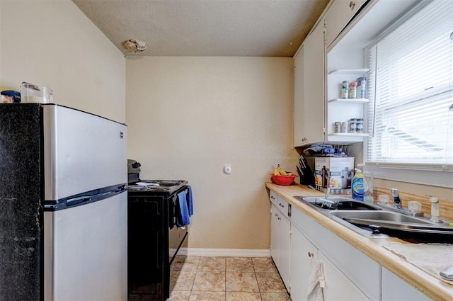 kitchen with light tile patterned flooring, sink, white cabinetry, electric range, and stainless steel refrigerator