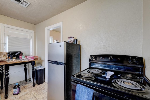 kitchen with light tile patterned flooring, stainless steel fridge, a textured ceiling, and black / electric stove