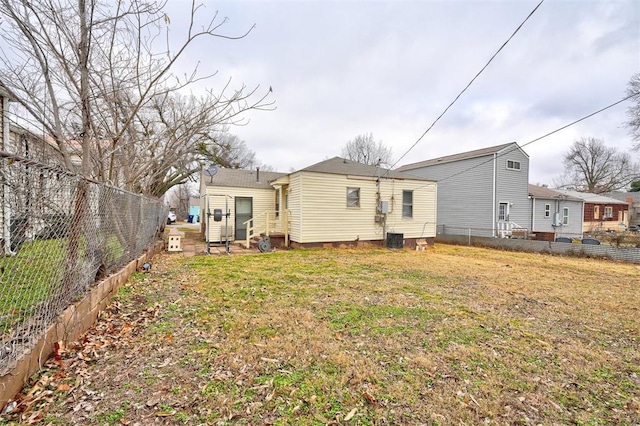 rear view of property with central air condition unit and a lawn