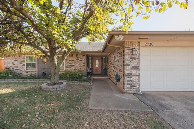 doorway to property with a garage and a yard