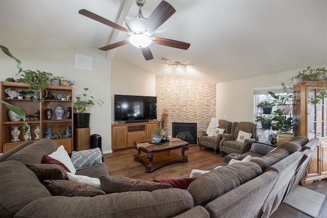 living room featuring lofted ceiling with beams, ceiling fan, a stone fireplace, and dark hardwood / wood-style flooring