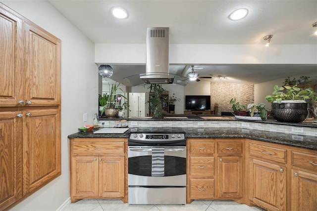 kitchen with light tile patterned flooring, island exhaust hood, stainless steel range with electric cooktop, and dark stone countertops