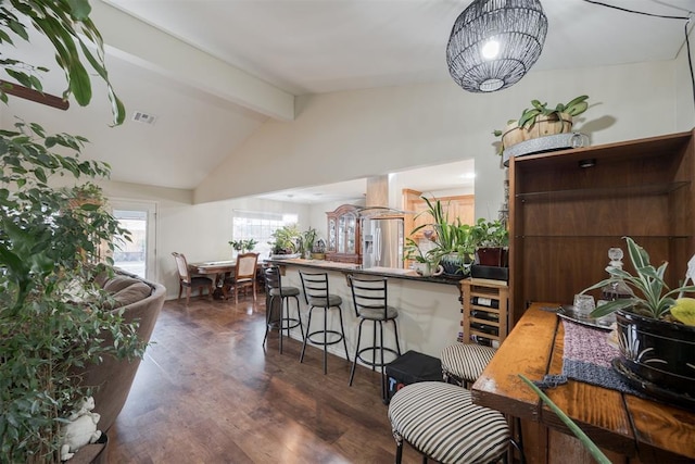 interior space featuring lofted ceiling with beams, stainless steel fridge with ice dispenser, dark hardwood / wood-style floors, a kitchen breakfast bar, and kitchen peninsula