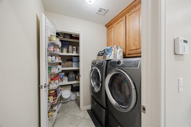 washroom with light tile patterned flooring, independent washer and dryer, and cabinets