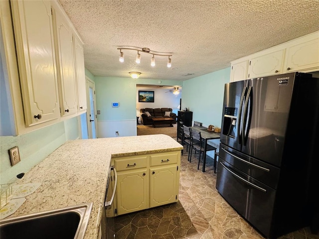 kitchen featuring sink, ceiling fan, track lighting, a textured ceiling, and black refrigerator with ice dispenser