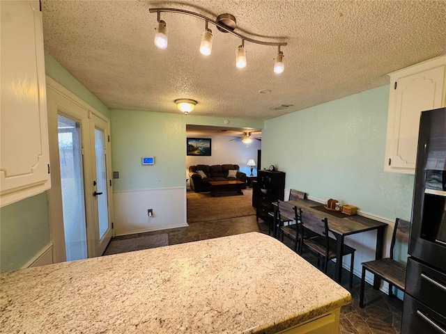 kitchen with ceiling fan, a textured ceiling, and white cabinets