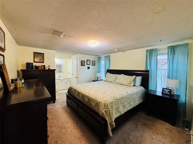 carpeted bedroom with connected bathroom and a textured ceiling