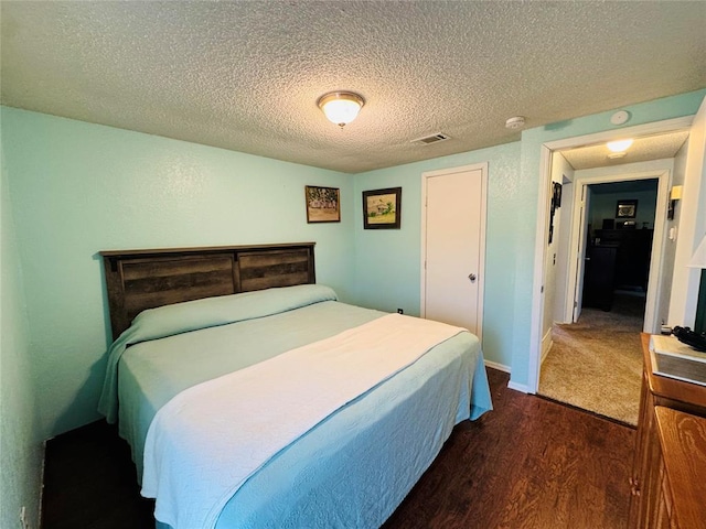 bedroom with dark hardwood / wood-style flooring and a textured ceiling