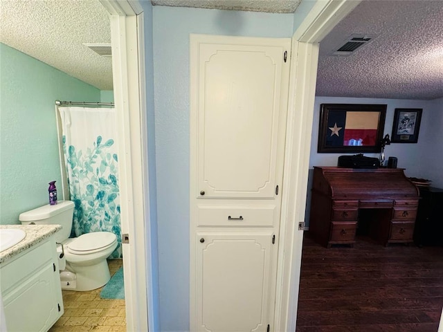 bathroom with walk in shower, toilet, a textured ceiling, vanity, and hardwood / wood-style flooring