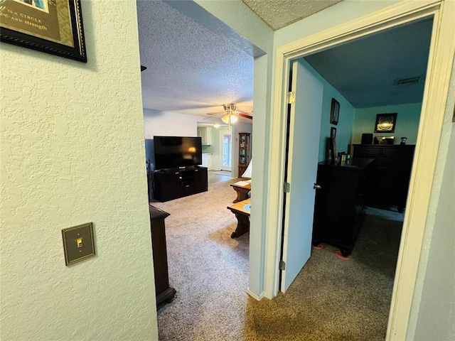 corridor featuring carpet flooring and a textured ceiling