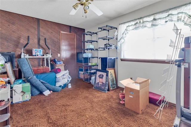 game room with ceiling fan, carpet flooring, a textured ceiling, and wooden walls