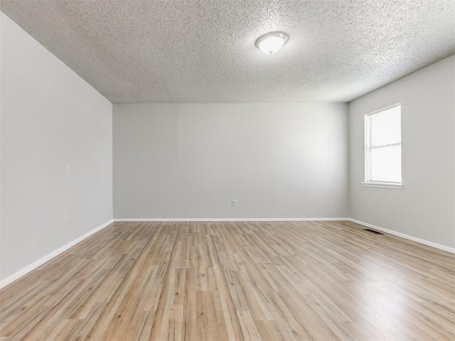 empty room with light hardwood / wood-style flooring and a textured ceiling