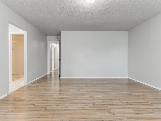 spare room with a textured ceiling and light wood-type flooring