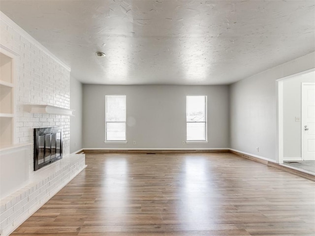 unfurnished living room with hardwood / wood-style floors, a brick fireplace, and a textured ceiling