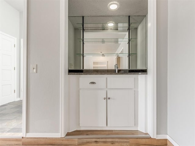 bar featuring dark stone countertops, sink, and white cabinets