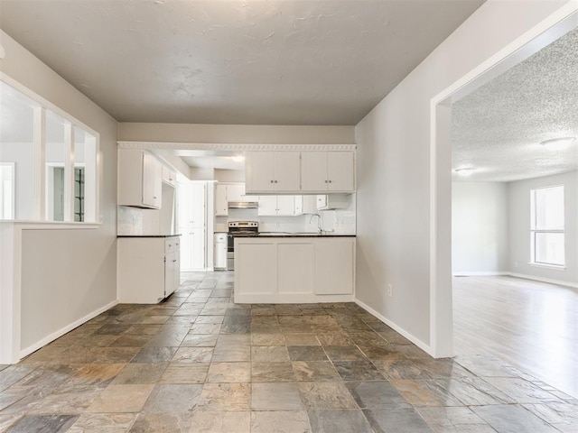 kitchen featuring electric stove, sink, white cabinetry, and a textured ceiling