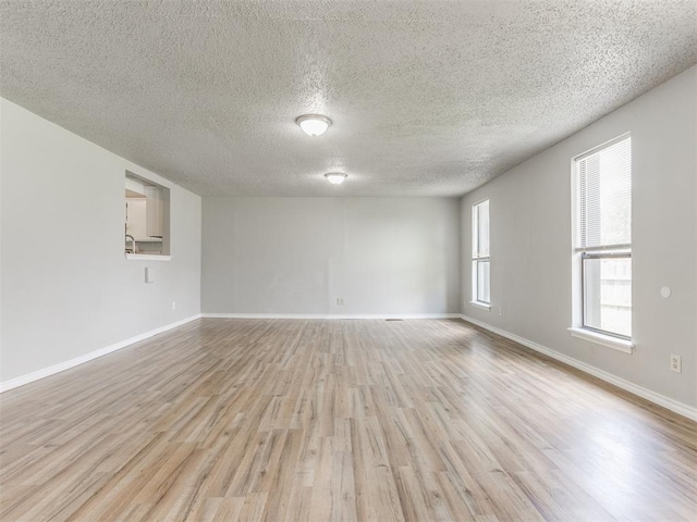 unfurnished room with a textured ceiling and light hardwood / wood-style floors