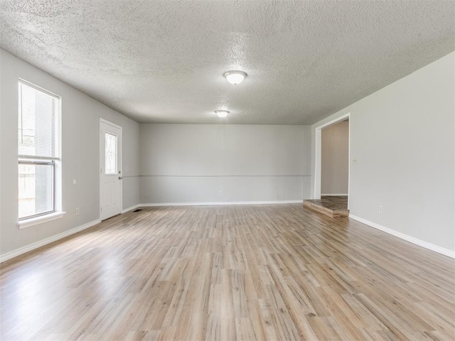 unfurnished room featuring a textured ceiling and light hardwood / wood-style flooring