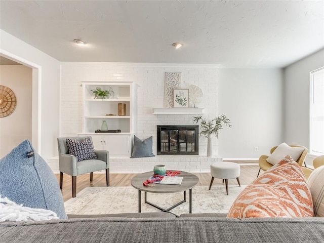 living area featuring a fireplace, built in shelves, and wood finished floors