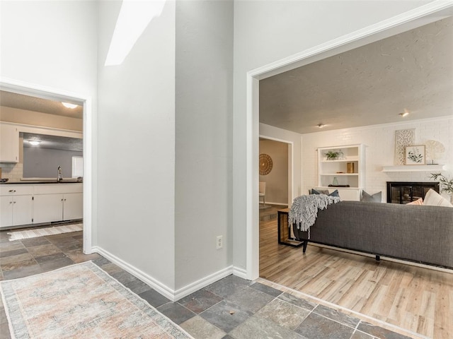 interior space featuring baseboards, a textured ceiling, stone tile flooring, and a fireplace