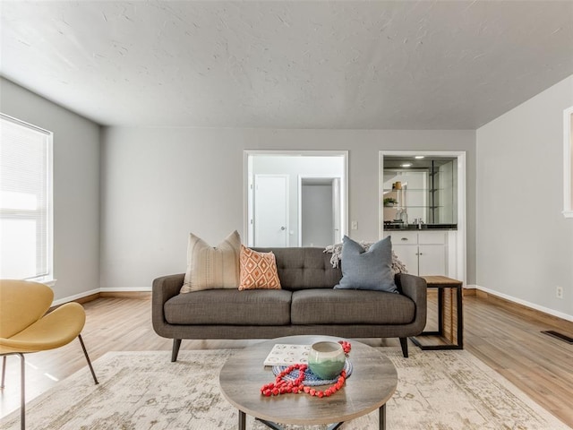 living room featuring visible vents, baseboards, and wood finished floors