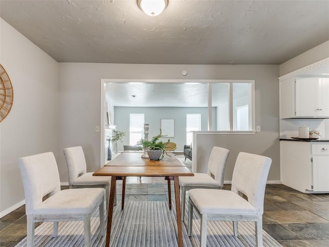 dining area with stone finish flooring, baseboards, and a textured ceiling