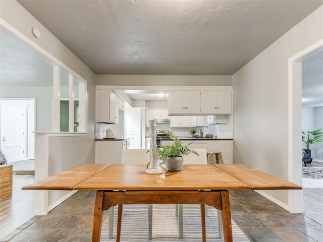 unfurnished dining area featuring stone finish flooring and baseboards