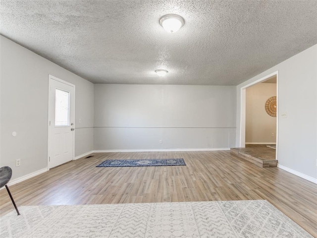 spare room featuring baseboards, a textured ceiling, and wood finished floors