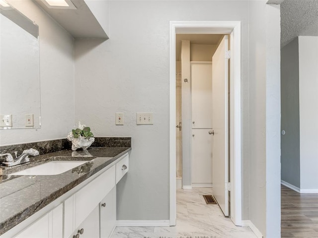 bathroom with vanity, visible vents, baseboards, and marble finish floor