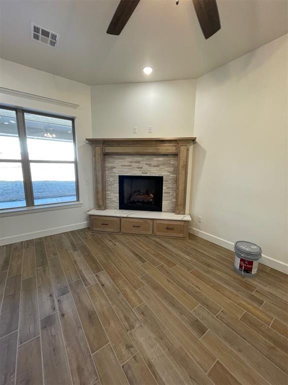 unfurnished living room with a fireplace, dark hardwood / wood-style floors, and ceiling fan