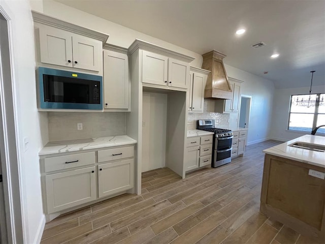 kitchen with sink, decorative backsplash, custom exhaust hood, double oven range, and light stone countertops