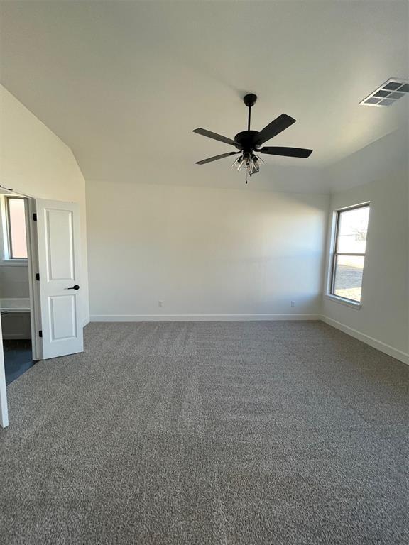 carpeted spare room with ceiling fan and vaulted ceiling