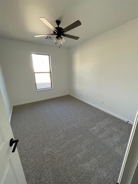 unfurnished room featuring ceiling fan and dark carpet