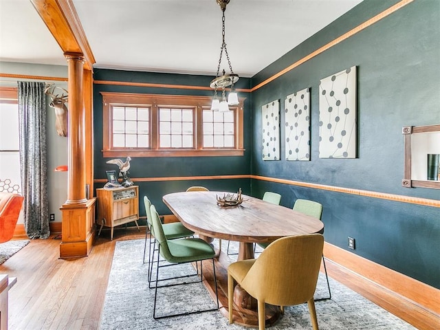 dining room with crown molding, plenty of natural light, decorative columns, and light wood-type flooring