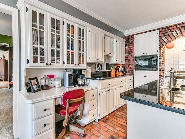 kitchen with sink, built in desk, black microwave, ornamental molding, and white cabinets