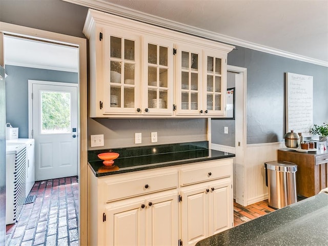 kitchen with white cabinetry, ornamental molding, and washing machine and clothes dryer