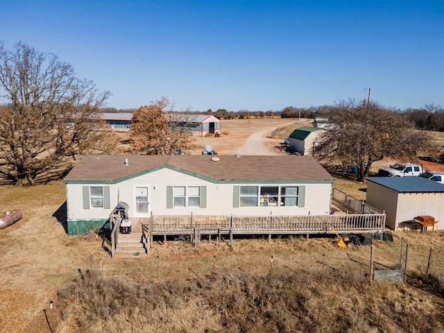 rear view of property featuring a storage shed and a deck