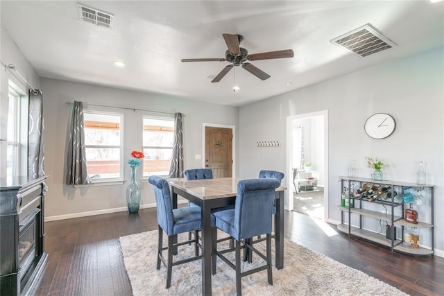 dining space featuring dark wood-type flooring, visible vents, and baseboards