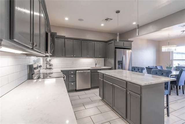 kitchen featuring a kitchen island, a sink, appliances with stainless steel finishes, decorative backsplash, and a kitchen bar