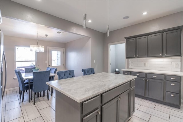 kitchen featuring a kitchen island, light countertops, backsplash, and gray cabinetry