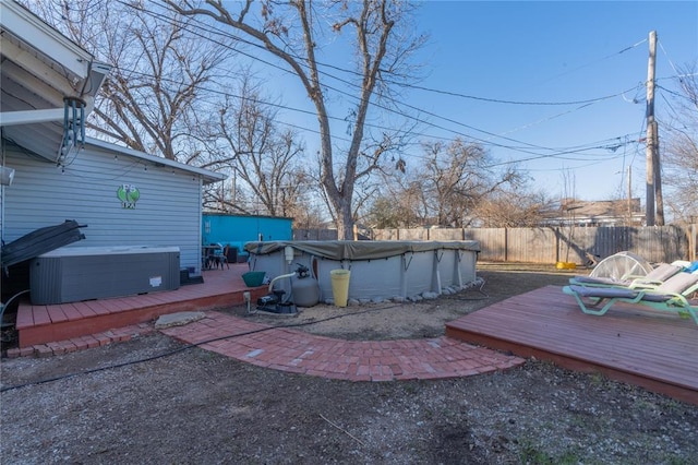 exterior space featuring a fenced in pool, a fenced backyard, a covered hot tub, a deck, and central AC